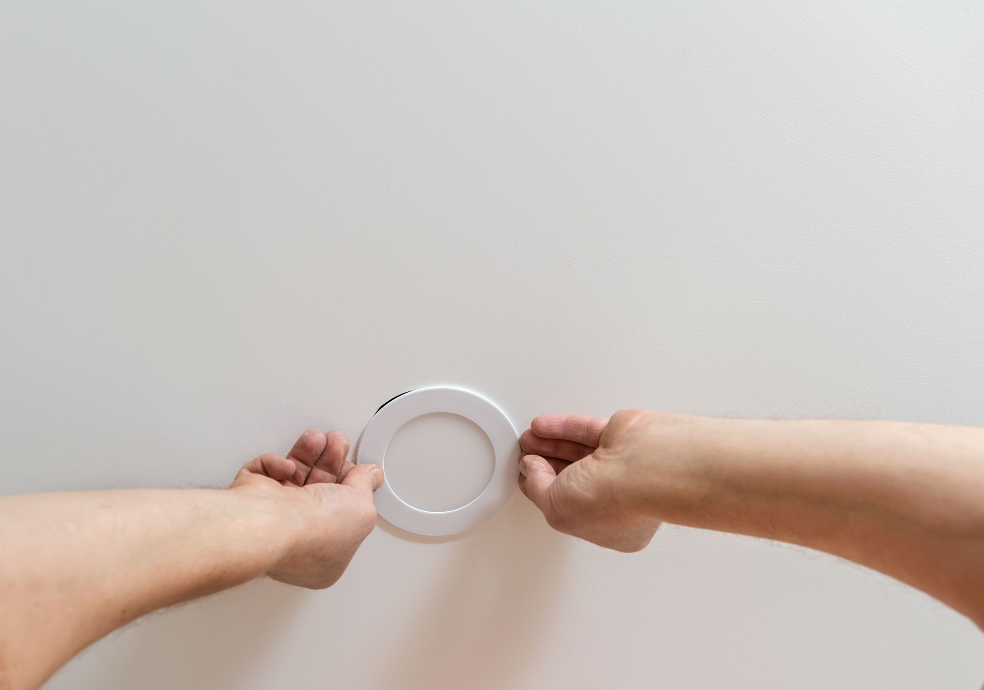 An electrician is installing an LED potlight pot light in the ceiling.